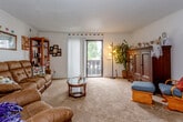 Located at 806 E Langsford Rd in Lee's Summit, Missouri, this single-floor residence offers a functional and comfortable layout across several well-defined living spaces. The living room serves as the heart of the home, featuring plush carpeted flooring, a textured ceiling, and a sliding glass door that opens to a private balcony, allowing natural light to fill the space and providing pleasant outdoor views. The living room flows openly into the dining area, which is illuminated by a ceiling fan with light fixture and offers a welcoming spot for everyday meals. The galley-style kitchen is thoughtfully arranged with white cabinetry, ample counter space, a double basin sink, and tile-style flooring, providing an efficient workspace for cooking and meal preparation. The bedroom is a generously sized carpeted retreat featuring a ceiling fan, a window with draping curtains, and ample room for furnishings including a full dresser and shelving. The bathroom includes a single-sink vanity with white cabinetry, a decorative tile backsplash, and a tub-shower combination, offering all the essentials in a compact, clean layout. Throughout the residence, a consistent and cozy character is maintained, making this Lee's Summit home a practical and inviting place to live.