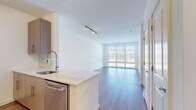 Located at 11500 Commerce Park Dr in Reston, Virginia, this modern single-floor residence offers a thoughtfully designed open-concept layout filled with natural light. The living area features light-toned hardwood flooring and a wall of large windows dressed with horizontal blinds, providing views of the surrounding Reston community and allowing abundant daylight to flow throughout the space. Track lighting accents both the living and secondary room areas, adding a contemporary touch.

The kitchen is well-appointed with flat-front wood-tone cabinetry, stainless steel appliances including a range and over-the-range microwave, a geometric-patterned tile backsplash, and light stone countertops extending to a peninsula with an undermount sink — ideal for both cooking and casual dining.

The bedroom is carpeted for comfort and features a large window that continues the home's bright aesthetic. A dedicated walk-in closet with wire shelving provides generous storage. The bathroom is finished with clean white tile in the tub-shower surround, large-format floor tiles, wood-tone cabinetry, and stone countertops, creating a clean and functional space.

Overall, the residence presents a modern, neutral palette with quality finishes throughout, offering a comfortable and stylish living environment in the heart of Reston, VA.