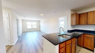 Located at 10095 Washington Blvd N in Laurel, MD, this single-floor, three-bedroom, two-bathroom home offers a well-organized and functional layout. The kitchen is a standout feature, showcasing warm honey-toned cabinetry, dark granite countertops, and a full suite of stainless steel appliances including a range, microwave, and refrigerator. A peninsula with an integrated sink adds prep space and connects the kitchen seamlessly to the living area, which features light hardwood-style flooring that extends throughout the main living spaces. The living room is bright and open, providing a clean, neutral canvas adaptable to various layouts. The spacious primary bedroom is carpeted for comfort and offers generous room for furnishings. The two additional bedrooms are similarly carpeted, with one featuring a window overlooking the outdoors. A central hallway connects the bedrooms to the two bathrooms — one with a tub-shower combination and white tile flooring, and the other with a standalone shower stall, also finished in white tile. The home maintains a clean, neutral palette with light gray walls and white trim throughout, creating a consistent and welcoming ambiance across every room.