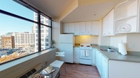 Located on the sixth floor at 201 Yesler Way in Seattle's historic Pioneer Square neighborhood, Unit 610 is a thoughtfully designed studio residence that makes excellent use of its single-floor layout. The unit features warm hardwood flooring throughout, clean white walls, and an open feel that maximizes the sense of space.

Large floor-to-ceiling windows are a defining architectural feature, flooding the interior with abundant natural light and framing striking views of the surrounding Seattle cityscape, including the neighboring urban buildings and streetscape below. These expansive windows are present in both the main living area and the sleeping space, creating a bright and airy atmosphere throughout the day.

The kitchen is efficiently designed in an L-shaped configuration, outfitted with ample white cabinetry extending to the ceiling for generous storage, a full-size refrigerator, an electric range, and a double-basin sink with gray countertops. A small dining area sits adjacent to the kitchen window, taking advantage of the city views.

The sleeping area is open and generously proportioned, with room for a bed and additional furnishings. A closet provides built-in storage. The bathroom features a clean, modern vanity with a white undermount sink, gray countertop, white cabinetry, and a large mirror with overhead lighting. The overall ambiance of the unit is bright, functional, and well-suited for urban living in the heart of Seattle.