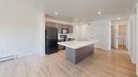 Located at 1265 Lear Ln in Hobart, WI, this single-story, 2-bedroom, 2-bathroom home offers a well-designed layout with modern finishes throughout. The open-concept kitchen and living area serves as the heart of the home, featuring a large center island with a striking marble-look countertop, a double sink, dark espresso cabinetry, black appliances including a refrigerator, range, and over-the-range microwave, and a dedicated pantry. Light wood-look flooring flows through the main living areas, while sliding glass doors provide natural light and outdoor views from the living space. Both bedrooms are carpeted and include ceiling fans, natural light from multiple windows, and access to closets. The primary bedroom offers a generously sized walk-in closet with wire shelving. The two bathrooms are finished with marble-look vanity countertops and dark cabinetry; one features a walk-in shower and the other a full tub/shower combo. A dedicated laundry room houses a full-size washer and dryer. The home also includes an attached garage, completing this functional and well-appointed single-floor residence.