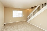 This two-floor residence offers a practical and comfortable layout designed for everyday living. The interior is finished with warm neutral tones throughout, creating a cohesive and inviting atmosphere across all rooms. Textured ceilings and clean white baseboards are consistent design elements found throughout the space.

The living area is generously sized, featuring plush wall-to-wall carpeting and a large window fitted with blinds that allows natural light to fill the room. Multiple bedrooms continue the same carpeted flooring and neutral color palette, each equipped with windows that bring in natural light. One of the bedrooms includes a dedicated walk-in closet, providing ample storage space. An additional bedroom features a louvered closet door for convenient wardrobe access.

The kitchen is efficiently laid out with light wood cabinetry, granite-style countertops, and a full suite of black appliances including a refrigerator, electric range, built-in microwave, and a sink. Wood-style flooring in the kitchen provides a practical contrast to the carpeted living areas.

The bathrooms are well-equipped, each featuring light wood cabinetry with open shelving above the toilet for additional storage. One bathroom includes a full tub-shower combination, while chrome hardware and towel bars add a polished finishing touch throughout.