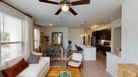This single-story residence in Conroe, Texas offers a thoughtfully designed open-concept floor plan that seamlessly connects the living, dining, and kitchen areas. The living room is bathed in natural light through multiple large windows dressed with blinds and sheer curtains, and features a ceiling fan overhead and wood-look flooring underfoot. The space flows naturally into the dining area, which offers room for a full-sized table and is positioned near a window for additional brightness.

The kitchen is a functional highlight, equipped with dark espresso cabinetry, granite countertops, a tile backsplash, stainless steel appliances—including a refrigerator, range, and microwave—and a kitchen island with pendant lighting above. The island also features a sink and bar seating, making it ideal for casual dining.

Both bedrooms are carpeted for comfort and include ceiling fans and windows with outdoor views. The second bedroom is well-sized with ample natural light. Each bathroom features a tub-shower combination with tile surround and dark cabinetry for storage. Throughout the unit, neutral tones and warm finishes create a cohesive, inviting ambiance.