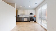 Located at 311 W 22nd St in Kansas City, MO, this efficiently designed one-bedroom, one-bathroom unit offers a well-planned single-floor layout. The open-concept kitchen and living area serves as the heart of the space, featuring light wood-look flooring, recessed lighting, and a large sliding window that floods the room with natural light and provides views of the surrounding cityscape. The kitchen is thoughtfully appointed with two-tone cabinetry — white upper cabinets paired with gray lower drawers — complemented by a classic white subway tile backsplash, dark countertops, and a full suite of stainless steel appliances including a refrigerator, range, microwave, and dishwasher. A hallway connects the main living area to the private bedroom, which is carpeted for comfort and features tall ceilings, a ceiling fan, and a sliding closet. Two closets provide additional storage throughout the unit. The bathroom includes a soaking tub with full subway tile surround and chrome fixtures, maintaining the clean, modern aesthetic found throughout. A dedicated utility room and in-unit laundry add everyday convenience to this smartly designed Kansas City residence.
