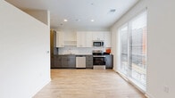 Located at 311 W 22nd St in Kansas City, MO, this efficiently designed one-bedroom, one-bathroom unit offers a well-planned single-floor layout. The open-concept kitchen and living area serves as the heart of the space, featuring light wood-look flooring, recessed lighting, and a large sliding window that floods the room with natural light and provides views of the surrounding cityscape. The kitchen is thoughtfully appointed with two-tone cabinetry — white upper cabinets paired with gray lower drawers — complemented by a classic white subway tile backsplash, dark countertops, and a full suite of stainless steel appliances including a refrigerator, range, microwave, and dishwasher. A hallway connects the main living area to the private bedroom, which is carpeted for comfort and features tall ceilings, a ceiling fan, and a sliding closet. Two closets provide additional storage throughout the unit. The bathroom includes a soaking tub with full subway tile surround and chrome fixtures, maintaining the clean, modern aesthetic found throughout. A dedicated utility room and in-unit laundry add everyday convenience to this smartly designed Kansas City residence.
