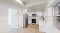 Located on Princeton Street in the heart of Santa Monica, CA, this thoughtfully designed single-floor unit offers a clean, modern aesthetic throughout. Light wood flooring runs seamlessly across every room, enhancing the bright and airy atmosphere created by generous natural light from multiple windows.

The kitchen is a standout feature, outfitted with white shaker cabinetry, quartz countertops, a subway tile backsplash, and a full suite of stainless steel appliances including a range, microwave, refrigerator, and dishwasher. A matte black faucet adds a contemporary accent.

The living and entry area features a tray ceiling detail, recessed lighting, and a warm wood front door that adds character to the otherwise crisp, white interior. The bedrooms are well-proportioned, each offering ample natural light through large windows and sliding mirror-door closets with built-in shelving for convenient storage.

Two bathrooms serve the unit, each finished with hexagonal floor tile and sleek matte black hardware. One bathroom features a frameless glass walk-in shower with full tile surround and a built-in niche, while the second offers a tub-shower combination with a sliding glass enclosure and a floating wood vanity. The overall ambiance is fresh, minimal, and move-in ready.