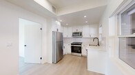 Located on Princeton Street in the heart of Santa Monica, CA, this thoughtfully designed single-floor unit offers a clean, modern aesthetic throughout. Light wood flooring runs seamlessly across every room, enhancing the bright and airy atmosphere created by generous natural light from multiple windows.

The kitchen is a standout feature, outfitted with white shaker cabinetry, quartz countertops, a subway tile backsplash, and a full suite of stainless steel appliances including a range, microwave, refrigerator, and dishwasher. A matte black faucet adds a contemporary accent.

The living and entry area features a tray ceiling detail, recessed lighting, and a warm wood front door that adds character to the otherwise crisp, white interior. The bedrooms are well-proportioned, each offering ample natural light through large windows and sliding mirror-door closets with built-in shelving for convenient storage.

Two bathrooms serve the unit, each finished with hexagonal floor tile and sleek matte black hardware. One bathroom features a frameless glass walk-in shower with full tile surround and a built-in niche, while the second offers a tub-shower combination with a sliding glass enclosure and a floating wood vanity. The overall ambiance is fresh, minimal, and move-in ready.