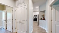 This single-floor residence features 2 bedrooms, 2 bathrooms, and 2 closets, all finished with a clean, contemporary aesthetic. Light gray walls, light wood-style flooring, and white trim create a cohesive, neutral palette throughout. The open-concept living room is a standout, offering generous proportions, a ceiling fan, and large windows with access to natural light and outdoor views. The kitchen is well-equipped with white shaker-style cabinetry, white subway tile backsplash, stainless steel appliances including a range, over-the-range microwave, dishwasher, and refrigerator, along with ample counter space and a double sink. A pass-through shelf connects the kitchen to the living area, enhancing the open flow. The primary bedroom is a comfortable retreat with plush carpet, a ceiling fan, and a dedicated walk-in closet outfitted with wire shelving and hanging rods. The second bedroom also features carpet and natural light. Both bathrooms are finished with white vanities and wood-style flooring; one includes a soaking tub with tile surround. The hallway provides convenient closet storage, and the layout as a whole offers a practical, well-organized floor plan suited for everyday living.