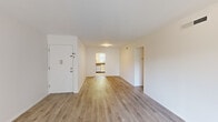 This well-designed 2-bedroom residence offers a clean, modern aesthetic across a thoughtfully organized single-floor layout. Light wood laminate flooring runs throughout the space, providing a warm and cohesive look from room to room. The open living area is bright and airy, featuring white walls and a neutral palette that maximizes the sense of space. Two hallways connect the living and sleeping areas seamlessly, contributing to a functional and intuitive flow.

The generously sized primary bedroom features a ceiling fan, vertical blinds covering a large window, and abundant natural light that fills the room. The second bedroom is equally well-appointed, also featuring a ceiling fan, a large window with vertical blinds, and the same light wood flooring, making it a versatile space suitable for a variety of uses.

The kitchen is equipped with white shaker-style cabinetry, dark granite-look countertops, a double stainless steel sink, subway tile backsplash, and a stainless steel dishwasher. A large window with vertical blinds above the sink allows for natural light and views of surrounding greenery, creating a pleasant workspace.

The unit is accessed through a solid entry door and maintains a clean, move-in-ready appearance throughout, with a bright and inviting ambiance defined by its light tones and consistent modern finishes.