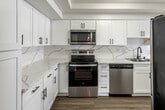 Located at 200 City Blvd W in Orange, California, this thoughtfully updated single-floor residence combines modern finishes with a functional layout. The kitchen serves as a standout feature, showcasing crisp white shaker cabinetry with matte black hardware, striking veined quartz countertops, and a matching full-height backsplash. Stainless steel appliances — including a range, over-the-range microwave, and dishwasher — complement the clean, contemporary aesthetic, while wood-look flooring ties the space together seamlessly. The open living and dining areas are bright and welcoming, featuring durable wood-look flooring, neutral warm-toned walls, and a fireplace accent. Sliding glass doors lead to a private balcony, inviting natural light and providing outdoor access. Plantation shutters on the windows offer both style and light control throughout. The carpeted bedroom provides a comfortable retreat, also fitted with plantation shutters. The bathrooms are finished with white cabinetry, quartz countertops, and a tub-shower combination with sliding glass doors. A large vanity mirror enhances the sense of space. Together, these elements create a cohesive, move-in-ready home with refined, modern touches at every turn.