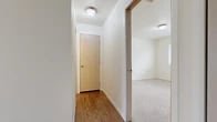 Located at 1715 S Hayford Rd in Airway Heights, WA, this one-bedroom, one-bathroom unit offers a well-organized single-floor layout designed for comfortable everyday living. The combined kitchen and living area forms the heart of the home. The galley-style kitchen features light wood cabinetry, laminate countertops, wood-look flooring, and full appliances including a refrigerator, electric range, and dishwasher. The adjoining living room is carpeted and highlighted by a white-framed fireplace, a wall-mounted air conditioning unit, and sliding glass door access alongside a window that brings in natural light and outdoor views of the surrounding landscape. The hallway, finished with warm wood-look flooring, connects the main living areas to the private spaces and includes ceiling light fixtures throughout. The bedroom is a comfortable, well-proportioned room with plush carpet, neutral walls, and a window offering natural light and exterior views. The full bathroom features a wood-toned vanity with an integrated sink, laminate countertop, and wood-look flooring, with a shower and curtain enclosure. A dedicated utility room provides added practicality and storage convenience within the overall layout.