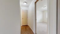 Located at 1715 S Hayford Rd in Airway Heights, WA, this one-bedroom, one-bathroom unit offers a well-organized single-floor layout designed for comfortable everyday living. The combined kitchen and living area forms the heart of the home. The galley-style kitchen features light wood cabinetry, laminate countertops, wood-look flooring, and full appliances including a refrigerator, electric range, and dishwasher. The adjoining living room is carpeted and highlighted by a white-framed fireplace, a wall-mounted air conditioning unit, and sliding glass door access alongside a window that brings in natural light and outdoor views of the surrounding landscape. The hallway, finished with warm wood-look flooring, connects the main living areas to the private spaces and includes ceiling light fixtures throughout. The bedroom is a comfortable, well-proportioned room with plush carpet, neutral walls, and a window offering natural light and exterior views. The full bathroom features a wood-toned vanity with an integrated sink, laminate countertop, and wood-look flooring, with a shower and curtain enclosure. A dedicated utility room provides added practicality and storage convenience within the overall layout.