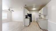 This single-story, 3-bedroom, 2-bathroom home offers a practical and comfortable layout designed to maximize every square foot. The living room greets residents with light-toned luxury vinyl plank flooring and a ceiling fan, creating a bright and airy atmosphere. A six-panel front door and window with blinds allow natural light to fill the space. The combined dining and kitchen area is a functional highlight, featuring white cabinetry lining both walls, black appliances including a refrigerator, range, and microwave, a stainless steel sink, and light countertops complemented by a subtle tile backsplash. The same durable vinyl plank flooring extends throughout the main living areas for a cohesive look. The three bedrooms offer soft wall-to-wall carpeting, ceiling fans, and windows with blinds that invite natural light. The spacious primary bedroom provides a generous retreat. Each of the two bathrooms includes a full tub-shower combination with clean, white surrounds. A dedicated laundry area accommodates a full-sized washer and includes overhead wire shelving for additional storage. Three closets throughout the home provide further organizational convenience, rounding out this efficient and move-in ready space.