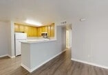 Located at 5 Hathaway Dr in Novato, CA, this single-floor residence offers four bedrooms and three bathrooms within a well-organized layout. The combined kitchen and living area serves as the heart of the home, where warm honey-toned wood cabinetry lines the walls of a fully equipped kitchen featuring a gas range, over-the-range microwave, refrigerator, and ample counter space. A peninsula with a breakfast bar connects the kitchen to the living area, which is finished with durable wood-style flooring that extends through the main living spaces and hallway. The living room opens to a private balcony through sliding glass doors, bringing in natural light and outdoor views of the surrounding greenery. The four bedrooms are carpeted for comfort, with neutral tones and windows that allow natural light to fill each room. The primary bedroom offers a generous footprint, providing ample space for a full furniture arrangement. The three bathrooms are functional and clean, each featuring tub-shower combinations with white tile surrounds, wood-toned vanity cabinetry, and wood-style flooring. A connecting hallway links all rooms cohesively, completing this practical and comfortable Novato residence.