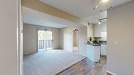 Located in Escondido, CA, this single-floor residence offers a practical and comfortable layout with two bedrooms and two bathrooms. The open-concept kitchen and living area serves as the heart of the home, featuring crisp white cabinetry, dark gray countertops, stainless steel appliances including a range and microwave, and wood-look vinyl flooring. A peninsula counter provides additional workspace and a natural transition into the adjoining living area. The living room is carpeted and filled with natural light from a sliding glass door that opens to a private balcony, offering outdoor views of the surrounding neighborhood. Both bedrooms are carpeted, finished in warm neutral tones, and equipped with ceiling fans for year-round comfort. Windows dressed with vertical blinds allow for adjustable natural light. The two bathrooms offer distinct configurations: one features a clean walk-in shower stall with accessibility grab bars, while the second includes a full tub-shower combination. Wood-look flooring carries through the bathroom spaces, maintaining a cohesive aesthetic. Textured ceilings are present throughout, adding subtle visual character. The hallway connects all rooms efficiently, contributing to the functional, well-organized flow of the overall floor plan.