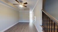 Located on Wilma Rudolph Boulevard in Clarksville, Tennessee, this two-story home is designed with a clean, contemporary aesthetic and thoughtful attention to detail throughout both levels. The main floor features durable hardwood-style flooring that flows through the open living and dining areas, complemented by neutral gray walls, crisp white crown molding, and bold white baseboards. Ceiling fans with integrated lighting fixtures are present in the main living spaces, enhancing comfort and airflow. A staircase with elegant dark wood treads and wrought iron balusters connects the two floors, adding a refined architectural accent.

The kitchen is well-appointed with rich, dark espresso cabinetry, granite-style countertops, and a full suite of stainless steel appliances including a French door refrigerator, electric range, over-the-range microwave, and dishwasher. A pantry with bifold doors provides additional storage nearby.

Upper-level bedrooms feature plush carpeting, tray ceilings, and windows that allow natural light to filter in. The bathroom includes tile flooring, a tub-shower combination, a dark vanity with a light countertop, and brushed nickel hardware, creating a practical and cohesive finish throughout the home.