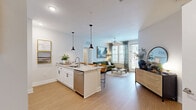 Located at 6050 Harbour Glenn Dr in Midlothian, VA, this thoughtfully designed two-bedroom, two-bathroom residence offers a comfortable and modern single-floor layout. Light-toned hardwood-style flooring flows throughout, complementing the bright, neutral palette that defines the space.

The open-concept kitchen and living area serves as the heart of the home. The kitchen features white shaker cabinetry, stainless steel appliances, a granite-topped island with seating for multiple guests, and stylish pendant lighting. This area transitions seamlessly into the living room, which benefits from large windows and a glass door that invite abundant natural light and provide direct outdoor access.

The primary bedroom is a well-proportioned retreat with a ceiling fan, large windows with views of the surrounding community, and access to a spacious walk-in closet outfitted with wire shelving systems for organized storage. The en-suite bathroom offers a glass-enclosed walk-in shower and a granite vanity with white cabinetry. The second bathroom features a full soaking tub with tile surround and brushed nickel fixtures.

A second bedroom provides flexible living space, and a connecting hallway with additional closet storage ensures practical functionality throughout. The overall ambiance is clean, modern, and welcoming.