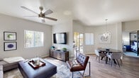 This single-story home showcases a thoughtfully designed open-concept layout that seamlessly connects the living, dining, and kitchen areas. The living room features vaulted ceilings with a ceiling fan, large windows that invite abundant natural light, and wood-look flooring that extends throughout the space. A sliding glass door leads to an outdoor patio, enhancing the indoor-outdoor flow. The dining area is accented by a stylish orb chandelier and benefits from additional natural light through a secondary sliding door.

The kitchen is well-equipped with rich wood cabinetry, white countertops, black appliances, and a breakfast bar with seating for casual dining. A dedicated hallway connects the private areas of the home, including the bedrooms and bathroom. The bathroom features a wood-toned vanity with a white countertop, a full tub-shower combination, and wood-look flooring. An in-unit laundry area with a full-size washer and dryer adds everyday convenience. Neutral gray walls and consistent flooring throughout create a cohesive, modern aesthetic.