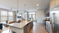 Located along Cheshire Bridge Road in Atlanta, GA, this well-appointed 2-bedroom, 1-bathroom residence offers a thoughtfully designed single-floor layout with modern finishes throughout. Wood-look flooring flows seamlessly from the entry hallway into the open-concept living and kitchen area, creating a cohesive and inviting atmosphere. 

The kitchen is a standout feature, boasting a large center island with a white quartz countertop, undermount sink, and seating along one side. Grey shaker-style cabinetry extends to the ceiling, complemented by a white subway tile backsplash and a full suite of stainless steel appliances. Pendant lighting above the island adds a stylish touch, while natural light pours in through large windows in the adjacent living area, which also features a ceiling fan.

The primary bedroom is generously sized, with large windows inviting natural light and direct access to a dedicated closet. The second bedroom is equally well-lit with its own closet space. The bathroom features grey cabinetry with white countertops, wood-look tile flooring, and a tiled shower enclosure, with convenient access to a walk-in closet. Additional highlights include four closets, an in-unit laundry room, a utility room, and a hallway connecting all areas efficiently.