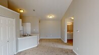 Located at 1946 Moray Ct E in Indianapolis, Indiana, this single-floor home presents an open-concept design defined by striking vaulted ceilings that lend a sense of spaciousness and architectural character throughout the main living area. Neutral-toned walls and wall-to-wall carpeting in the living spaces create a clean, cohesive aesthetic, while tile flooring transitions through the kitchen and bathroom areas.

The kitchen is equipped with white cabinetry offering ample storage, speckled laminate countertops, a peninsula with a built-in sink, a coil-burner electric range, a refrigerator, and an overhead exhaust hood. The peninsula layout opens directly to the living area, supporting an easy flow between cooking and entertaining spaces.

The bedroom is a standout feature, showcasing a dramatic vaulted ceiling and a large arched window that draws in considerable natural light and views of the surrounding exterior. A double-door closet provides generous storage within the room.

The full bathroom includes a wide vanity with speckled countertop, a large wall mirror with a lighted fixture above, a toilet, and a shower-tub combination. Tile flooring and white cabinetry below the vanity complete the space with a functional, well-maintained finish throughout.