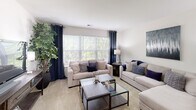 Located at 2113 Bromley Park Dr in Winston-Salem, NC, this single-floor residence offers a well-designed layout with a comfortable and cohesive living environment. The spacious living room is a standout feature, bathed in natural light through large windows dressed with navy curtains that frame views of lush greenery outside. Plush carpeting and an open feel make this area ideal for relaxing or entertaining. A tiled entryway transitions smoothly into the carpeted living space, providing both practicality and style. The kitchen is efficiently laid out with ample white cabinetry extending to the ceiling, white appliances including a range and refrigerator, light countertops, and tile flooring, all illuminated by track lighting overhead. Multiple bedrooms offer comfortable retreats, each carpeted and featuring closet storage. The bedrooms are bright and well-proportioned, with windows allowing in natural light. The bathrooms are finished with tile flooring and include a tub-shower combination. A dedicated in-unit laundry area with a full-size washer and dryer adds notable convenience. Throughout, the residence maintains a clean, neutral color palette that creates a calm and inviting atmosphere.