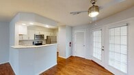 This two-story residence offers a practical and well-organized layout spread across two floors. The main level serves as the social hub of the home, featuring an open-concept kitchen and living area finished with warm hardwood-style flooring throughout. The kitchen is equipped with stainless steel appliances, including a range, microwave, and refrigerator, complemented by white shaker-style cabinetry and light granite countertops that extend across a peninsula with an integrated sink. A ceiling fan with a light fixture anchors the living area, which benefits from natural light through a windowed entry door. A bathroom on the main level features a white vanity with granite countertop, a framed mirror, and gold-tone hardware accents.

The upper floor houses all three bedrooms and additional bathrooms. The spacious primary bedroom provides ample room for furnishings, while the additional bedrooms offer comfortable dimensions with neutral walls and carpet flooring. One bedroom includes a sliding glass door providing access to natural light and outdoor views. Bathrooms feature tub-shower combinations with clean white surrounds. Neutral light gray walls are consistent throughout, lending the home a cohesive and move-in ready aesthetic.