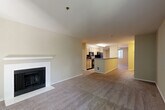 Located in Redmond, WA, this 2-bedroom, 2-bathroom residence offers a well-designed single-floor layout that balances comfort and functionality. The open-concept living and dining area is anchored by a tiled fireplace with a clean white mantel, providing a welcoming focal point. Plush wall-to-wall carpeting runs throughout the main living spaces and bedrooms, while neutral-toned walls create a bright, cohesive atmosphere. Sliding glass doors lead to a private balcony with views of surrounding greenery, allowing natural light to fill the room.

The galley-style kitchen features light wood cabinetry, dark granite-style countertops, and black appliances including a range, microwave, refrigerator, and dishwasher. A breakfast bar peninsula opens toward the living area, enhancing the sense of connectivity between spaces.

The spacious primary bedroom offers generous proportions and ample closet space, while the second bedroom also includes a closet and soft carpeting. Both bathrooms are finished with light wood vanities, dark countertops, and tile flooring. One bathroom includes a full soaking tub, while the other features a well-lit vanity with a large mirror. This thoughtfully laid-out residence is ideally situated in the heart of Redmond's established community.
