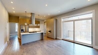Located in Chicago's vibrant Lower West Side neighborhood, this modern 3-bedroom, 2-bathroom residence offers thoughtfully designed living across two floors. Wide-plank hardwood flooring flows throughout, complemented by neutral toned walls and recessed lighting that create a bright, cohesive aesthetic.

The open-concept living area seamlessly integrates the kitchen, dining, and living spaces. The contemporary kitchen is a standout, featuring a large center island with a gas cooktop and striking stainless steel range hood overhead, flat-panel cabinetry in warm taupe tones, stainless steel appliances including a French door refrigerator and built-in microwave, and sleek white countertops. Pendant lighting adds a refined touch. Sliding glass doors lead directly to a private balcony with views of the surrounding Chicago streetscape.

The primary bedroom is generously proportioned and includes an en-suite bathroom with a walk-in glass-enclosed shower finished in crisp white tile. A second full bathroom offers a soaking tub with floor-to-ceiling tile surround. The two additional bedrooms feature multiple windows for natural light. Four closets provide ample storage throughout. The home also includes a patio and hallway, rounding out a well-organized and functional floor plan suited for comfortable urban living.