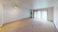 Located at 4057 S 35th St in Greenfield, Wisconsin, this single-floor residential unit offers a functional and straightforward layout designed for comfortable everyday living. The expansive main living area is carpeted and filled with natural light, featuring a ceiling fan, a sliding glass door that opens to an outdoor view, and baseboard heating that runs throughout the space. A staircase visible from the living area leads to additional levels, adding architectural interest to the open floor plan. The galley-style kitchen is efficiently arranged with white cabinetry lining both walls, a gas range, refrigerator, double sink with laminate countertops, and easy-to-clean vinyl flooring — providing ample storage and workspace. The bedroom is generously sized with plush carpeting, a large sliding-door closet offering substantial storage, and a wide window with vertical blinds that allows in plenty of natural light. The bathroom features an extended vanity countertop with a single basin sink, louvered cabinet doors, a large mirror, and a separate water closet housing a full-size soaking tub with a tiled shower surround. Baseboard heating is consistent throughout, and the clean, neutral palette creates a bright and welcoming atmosphere throughout the home.