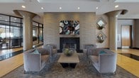 Located at 5455 N Marginal Rd in Cleveland, Ohio, this elegantly designed lobby space makes a strong architectural statement from the moment of entry. The main entrance features expansive floor-to-ceiling glass walls and doors that flood the interior with natural light, offering views of the surrounding landscape. Structural columns with curved, sculptural caps are a recurring design element throughout, adding a sense of refined modernism to the open layout.

The flooring is a standout feature, composed of a rich combination of polished marble, warm terra-cotta stone tiles, and dark granite inlay strips that guide movement through the space. Textured wall treatments in layered earth tones and wave-like patterns provide visual depth and complement the neutral color palette.

A dedicated seating lounge anchors one section of the lobby, centered around a sleek fireplace framed by a dramatic textured stone surround. Plush upholstered chairs and a low coffee table create an inviting gathering area, accented by contemporary artwork and decorative botanicals. Additional seating areas with accent chairs are positioned throughout, offering multiple comfortable vantage points.

A reception console and curated wall art add functional and aesthetic detail to the corridors. Recessed lighting and large pendant fixtures ensure consistent, warm illumination across the space, enhancing its polished, professional ambiance.