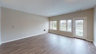 This two-story residence at 205 Mt Hope Ave in Rochester, NY offers a well-designed layout spread across two levels. The main floor features an open-concept living area with durable hardwood-style flooring and neutral-toned walls that create a bright, welcoming atmosphere. Large windows flood the space with natural light while framing pleasant outdoor views of the surrounding greenery. A door provides direct access to an outdoor area, adding to the unit's connectivity with its surroundings.

The kitchen is positioned adjacent to the living area and features light wood cabinetry, granite-style countertops, stainless steel appliances including a refrigerator, microwave, and range, and tile flooring. A peninsula counter separates the kitchen from the living space, enhancing the open feel. A staircase leads to the upper level, where carpeted bedrooms offer a quieter retreat. The bedrooms are generously sized, with large windows providing views of the neighborhood and surrounding area, including nearby water views visible from select rooms.

The bathroom is finished with large-format tile flooring, a tiled tub surround, a soaking tub, and a wood-toned vanity with stone countertops, completing this functional and cohesive space.