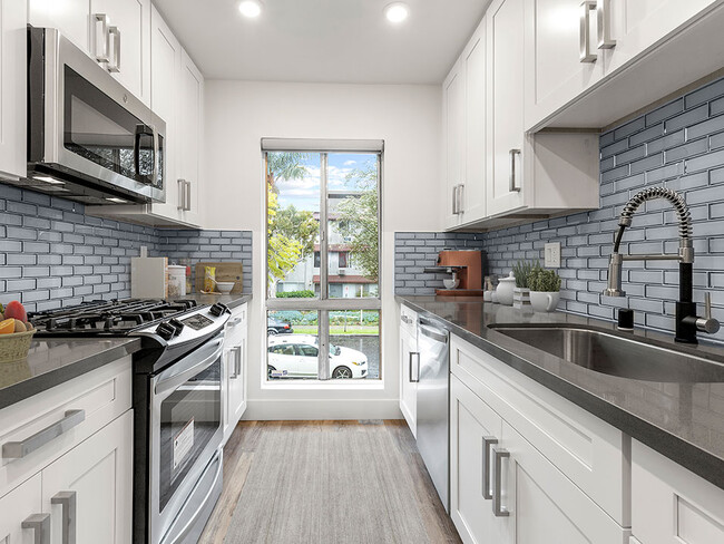 Blue tiled kitchen with stainless steel microwave, oven, and fixtures. - The Glendon Building