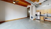 Located in the heart of St. Louis on Washington Avenue, this 1-bedroom, 1-bathroom loft showcases a compelling blend of industrial character and modern functionality. The open-concept main living area combines the living room, dining room, and kitchen into one expansive, light-filled space. Large black-framed windows invite abundant natural light and frame views of the surrounding urban streetscape. Overhead, warm wood plank ceilings with exposed timber beams and visible ductwork lend an authentic loft aesthetic, while polished concrete floors run seamlessly throughout.

The kitchen is well-appointed with light maple cabinetry, dark countertops, stainless steel appliances including a refrigerator, range, microwave, and dishwasher, and a modern circular pendant light fixture. An in-unit washer is conveniently situated nearby. A hallway with a sliding barn-style wood door connects the main living area to the private bedroom, which features the same exposed beam ceiling and generous proportions. Three closets provide ample storage throughout. The bathroom offers a full tub-shower combination with clean white tile surround. The unit also includes a dedicated laundry area, completing this well-designed urban loft.