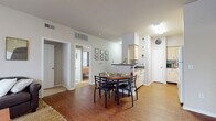 Located at 5802 W Jefferson Commons Circle in Kalamazoo, Michigan, this single-floor residence offers a well-organized layout designed for functional, everyday living. The living room serves as the social heart of the unit, featuring warm hardwood-style flooring, a large window with a glass door that invites abundant natural light, and enough space to accommodate generous seating arrangements. Neutral wall tones throughout create a calm, cohesive atmosphere.

The kitchen is laid out in a galley style with cream-toned cabinetry, dark countertops, hardwood-style flooring, and white appliances including a range, microwave, and dishwasher. It opens toward a dedicated dining area, which comfortably fits a round table with seating for four, making the transition between cooking and dining seamless.

Multiple bedrooms provide private retreats, each carpeted and equipped with windows that allow natural light. Several rooms feature built-in desks and mirrored sliding closet doors, offering practical storage and workspace solutions. The bedrooms vary slightly in size and character while maintaining a consistent, neutral aesthetic.

Two bathrooms serve the unit, each featuring hardwood-style flooring, light cabinetry with dark countertops, and shower-tub combinations, providing functional and tidy spaces for daily routines.