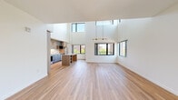 Located at 435 Alexander Loop in Eugene, Oregon, this contemporary two-story home offers 3 bedrooms and 3 bathrooms across a well-designed layout. The main floor is the larger of the two levels and centers around a striking open-concept living and kitchen area distinguished by dramatic double-height ceilings and an abundance of natural light streaming through oversized black-framed windows. The kitchen features warm wood cabinetry, a center island with clean countertops, open shelving, and stainless steel appliances, with views of the surrounding greenery. Light wood-tone flooring flows throughout the main level, enhancing the bright, airy atmosphere. A hallway connects the main living areas to additional rooms, with a carpeted staircase leading to the upper floor. The upper level offers a more intimate setting with plush carpeted flooring and an open loft-style landing that overlooks the living area below. Bedrooms are generously proportioned, with the spacious primary suite featuring a walk-in closet. Additional bedrooms include ample closet storage and windows with neighborhood views. The bathrooms are finished in a clean, minimalist style with white tile surround tub-shower combinations and wood-tone flooring. The overall design aesthetic is modern and cohesive throughout.