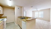 Located at 7400 Hogan Rd in Jacksonville, FL, this two-bedroom, two-bathroom residence offers a functional and comfortable single-floor layout. The open-concept kitchen is a central feature, equipped with light wood cabinetry, laminate countertops, a double-basin sink, a dishwasher, and an electric range. A peninsula counter extends into the space, providing additional prep area and creating a natural transition into the adjoining living room. The living area is bright and welcoming, benefiting from a large window that allows natural light to fill the room, complemented by a ceiling fan overhead and soft carpeting underfoot. Wood-look plank flooring runs through the kitchen and bathrooms, adding a cohesive visual flow. The primary bedroom is a comfortable, well-proportioned retreat with its own ceiling fan, a window for natural light, and plush carpeting. The second bedroom offers similar finishes in a cozy, versatile space. Both bathrooms are finished with wood-tone vanity cabinetry and laminate countertops; one features a full tub-shower combination with tile surround and wood-look flooring. Two closets provide practical storage throughout the home. The neutral, warm color palette across all rooms creates a clean and inviting atmosphere throughout.