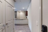 This thoughtfully designed 2-bedroom, 2-bathroom single-story residence offers a comfortable and functional layout with quality finishes throughout. The kitchen serves as a central highlight, featuring rich dark wood cabinetry, granite countertops, stainless steel appliances including a French door refrigerator and range, and a peninsula with bar seating that opens seamlessly to the living area. Recessed lighting and wood-style flooring give this space a clean, modern aesthetic.

The living area extends toward a glass door and large window fitted with blinds, allowing natural light to flow in while offering views to the outdoors. Ceiling fans are present in both the living area and bedrooms, adding to the overall comfort of the home.

Both bedrooms are carpeted and well-sized, with the primary bedroom offering multiple windows and ample natural light. The bedrooms are supported by five closets throughout the unit, including walk-in storage with built-in shelving rods. The bathrooms are finished with granite-topped dark wood vanities and wood-style flooring, with one featuring a tub-shower combination with tiled surrounds.

Additional practical spaces include a laundry room, pantry, utility room, and hallway, making this a highly functional and organized home.