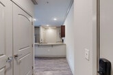 This thoughtfully designed 2-bedroom, 2-bathroom single-story residence offers a comfortable and functional layout with quality finishes throughout. The kitchen serves as a central highlight, featuring rich dark wood cabinetry, granite countertops, stainless steel appliances including a French door refrigerator and range, and a peninsula with bar seating that opens seamlessly to the living area. Recessed lighting and wood-style flooring give this space a clean, modern aesthetic.

The living area extends toward a glass door and large window fitted with blinds, allowing natural light to flow in while offering views to the outdoors. Ceiling fans are present in both the living area and bedrooms, adding to the overall comfort of the home.

Both bedrooms are carpeted and well-sized, with the primary bedroom offering multiple windows and ample natural light. The bedrooms are supported by five closets throughout the unit, including walk-in storage with built-in shelving rods. The bathrooms are finished with granite-topped dark wood vanities and wood-style flooring, with one featuring a tub-shower combination with tiled surrounds.

Additional practical spaces include a laundry room, pantry, utility room, and hallway, making this a highly functional and organized home.