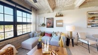 This industrial-modern loft showcases a striking blend of raw architectural character and contemporary design. Soaring exposed concrete ceilings with visible structural elements and piping set a distinctive loft aesthetic throughout the space, while polished concrete floors tie each room together seamlessly.

The open-concept kitchen and living area serves as the heart of the unit. The kitchen is well-appointed with warm wood cabinetry, a deep navy tile backsplash, stainless steel appliances including a full-size refrigerator, range, microwave, and dishwasher, and generous counter space. The living room is bathed in natural light through oversized, black-framed industrial windows that frame outdoor views, creating an airy and inviting atmosphere.

The bedroom offers a comfortable and private retreat, featuring the same exposed concrete ceiling and a closet with built-in shelving. A hallway connects the main living areas to the bedroom and bathroom, maintaining a clear and functional layout.

The bathroom is finished with warm wood vanity cabinetry, a grey composite countertop, matte black fixtures, and a full tub-shower combination with white subway tile surround. Every detail reflects a cohesive industrial-modern design sensibility, making this a distinctive and characterful living space.