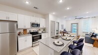 This well-appointed 2-bedroom, 2-bathroom residence in Baton Rouge, Louisiana offers a thoughtfully designed single-floor layout with modern finishes throughout. The open-concept kitchen is a standout feature, showcasing white shaker cabinetry, granite countertops, a subway tile backsplash, stainless steel appliances including a range, microwave, and refrigerator, and a peninsula island with an undermount sink — ideal for both cooking and casual dining. Light wood-style flooring flows seamlessly throughout the space, enhancing the bright, airy atmosphere created by recessed lighting and crisp white walls. The living room is comfortable and functional, featuring a ceiling fan, large windows with sheer drapes, and a glass door that opens to the outdoors, inviting natural light and fresh air. Both bedrooms are generously sized, each equipped with ceiling fans and windows that fill the rooms with natural light. The primary bedroom offers a calm, restful retreat with ample space. Each bathroom features granite-topped white vanities, tile flooring, and direct access to a dedicated closet with built-in shelving and hanging rods — providing excellent storage and organization. This residence combines clean, contemporary design with practical amenities for comfortable everyday living.