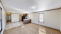 Located at 2600 University Ave in Williston, ND, this single-floor, 3-bedroom, 2-bathroom home offers a practical and functional layout suited for comfortable everyday living. The open-concept kitchen and dining area flows seamlessly into the spacious living room, creating a connected and versatile common space. The kitchen features dark wood cabinetry, a peninsula with built-in dishwasher, black appliances including a range and refrigerator, and light tile-style flooring that transitions into plush wall-to-wall carpeting in the living and bedroom areas. Crown molding with dark trim accents runs throughout, adding a clean, finished look to each room. Natural light enters through blinded windows in the living area and bedrooms, brightening the neutral-toned walls. The generously sized primary bedroom includes its own closet and window with outdoor views. Two additional bedrooms offer comfortable proportions with carpet flooring and dedicated closets. Both bathrooms are finished with tile-style flooring, vanities with marble-patterned countertops, and tub/shower combinations. A dedicated laundry area with washer and dryer units and overhead wire shelving adds everyday convenience. Three closets provide ample storage throughout the home.