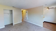 This single-floor residential unit offers a practical and comfortable layout with consistent neutral tones throughout. The living area welcomes you through a front entry door with wood-style flooring at the threshold, transitioning to plush carpet that extends across the open space. A large window lets in natural light and offers outdoor views, while a wall-mounted air conditioning unit ensures year-round comfort. Textured ceilings are found throughout the unit, adding a classic residential character.

The bedrooms are carpeted and feature neutral beige walls, flush-mount ceiling light fixtures, and windows that frame views of surrounding greenery. Closet access is available in the bedroom areas, providing practical storage solutions.

The galley-style kitchen is efficiently designed with white cabinetry above and below the counter, a double-basin stainless steel sink, light-toned countertops, and wood-style vinyl flooring. White appliances, including a refrigerator and range, complete the kitchen's functional setup.

The bathroom is clean and simply appointed, featuring a full-size soaking tub with an overhead shower, a curtain rod, and white cabinetry for storage. The overall ambiance of the unit is understated and move-in ready, offering a comfortable and functional living environment.