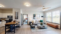 This single-floor residence offers a thoughtfully designed open-concept layout that seamlessly connects the living, dining, and kitchen areas. The living room is bright and welcoming, featuring light wood-style flooring, a ceiling fan, and windows that allow natural light to fill the space. A comfortable sofa, glass coffee table, and carefully chosen artwork contribute to the room's modern, relaxed aesthetic.

The kitchen is efficiently laid out with white cabinetry, dark countertops, and black appliances, including a full-size refrigerator, range, and microwave. A butcher-block island with bar seating provides a casual dining option and adds warmth to the space.

The bedroom is carpeted and generously proportioned, accommodating a full bed with ease while leaving ample room for additional furnishings. Multiple windows bring in natural light, and the room includes access to a spacious walk-in closet outfitted with wire shelving and hanging rods for organized storage.

The bathroom is clean and contemporary, featuring a single vanity with white cabinetry, a large mirror, and modern fixtures. Neutral tones throughout create a cohesive and calm atmosphere. Overall, this residence combines functional design with modern finishes to deliver a comfortable and practical living environment.