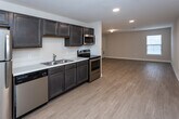 Located at 168 Bass Pro Dr in Sevierville, Tennessee, this single-floor unit offers a practical and well-appointed layout designed for comfortable everyday living. The open-concept design connects the kitchen directly to a spacious living area, creating a seamless flow throughout the main living space. Light wood-style flooring runs throughout the common areas, lending a clean and modern aesthetic.

The kitchen is fully equipped with a full suite of stainless steel appliances, including a refrigerator, electric range, over-the-range microwave, and dishwasher. Rich dark cabinetry provides ample storage and contrasts neatly with the light countertops and neutral wall tones. Recessed lighting illuminates the kitchen and main living areas effectively.

The bedrooms feature soft wall-to-wall carpeting and are brightened by windows with blinds that allow for natural light. The bathrooms are finished with dark vanity cabinetry, white countertops, and well-lit vanity mirrors, maintaining a consistent design palette throughout the unit. A dedicated laundry area with a stacked washer and dryer unit adds convenience. The overall ambiance is clean, neutral, and move-in ready, making it a functional and comfortable space in the heart of Sevierville.