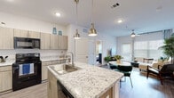 Located at 101 Pine Forest Rd in Augusta, Georgia, this single-story residence offers a thoughtfully designed open-concept layout that seamlessly connects the kitchen, dining, and living areas. The kitchen is a standout feature, equipped with light wood cabinetry, granite-topped counters, black stainless appliances including a range, microwave, refrigerator, and dishwasher, and a central island with a stainless steel sink illuminated by brushed nickel pendant lights. Wood-look flooring flows throughout the main living areas, enhancing the bright, airy ambiance created by recessed lighting and large windows. The living room is generously proportioned, with a ceiling fan, oversized windows with blinds, and direct access to an outdoor area. The bedrooms are carpeted and well-lit by natural light through sizable windows, providing a comfortable retreat. The primary bedroom connects to a full bathroom featuring a dual-sink granite vanity, wood-toned cabinetry, and a soaking tub with a tiled surround. A walk-in closet with wire shelving adds practical storage. The exterior includes landscaped green space, a covered gazebo, and a pergola-style outdoor area, contributing to the welcoming curb appeal of this Augusta property.