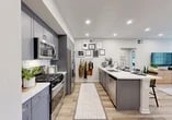 Located at 559 E Arnuado Blvd in Tracy, CA, this single-story home offers a well-designed layout across a comfortable footprint. The open-concept kitchen and living area serves as the heart of the home, showcasing sleek gray shaker cabinetry, white quartz countertops, a white subway tile backsplash, and stainless steel appliances including a gas range. A generous center island with bar seating provides both additional prep space and a casual dining area. Light wood-style flooring runs throughout the main living spaces, complementing the bright, neutral palette. The living room is filled with natural light from large windows and a glass door, creating an airy, welcoming atmosphere. The bedroom is a serene retreat featuring plush carpeting, a ceiling fan, and a window that allows in natural light. Adjacent to the bedroom is a dedicated walk-in closet with dual hanging rods and ample storage. The bathroom features a dual-sink vanity with gray cabinetry, white quartz countertops, a large mirror, and wood-style flooring. Recessed lighting throughout the home ensures a bright, modern feel, while the neutral tones and clean finishes create a cohesive and inviting living environment.