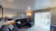 This two-floor residence offers a thoughtfully arranged layout across its multiple rooms, blending comfort and functionality throughout. The living room serves as the heart of the home, featuring soft carpeting, neutral-toned walls, and a large sliding glass door fitted with vertical blinds that allows natural light to flow in while offering access to an outdoor area. An ornate mirror and warm accent lighting add character to the space.

Adjacent to the living area is a dedicated dining space with hardwood-style flooring, offering a cozy setting for meals. The kitchen is efficiently designed with white cabinetry, granite-style countertops, a double stainless steel sink, and ample storage space throughout.

The primary bedroom is generously sized with plush carpeting, a large window with blinds, and a spacious closet with bifold doors. A second bedroom provides a comfortable, carpeted retreat with natural light and charming wall décor. Both rooms carry a calm, restful ambiance.

The bathroom features a full bathtub and shower combination with clean white tile surround, completing the functional offerings of the home. Overall, the residence presents a warm, livable environment with consistent neutral tones, soft textures, and practical design elements across all floors.