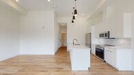 Located in Denver's vibrant West Highland neighborhood, this modern 4-bedroom, 2-bathroom residence offers a thoughtfully designed single-floor layout. The open-concept kitchen and living area serves as the heart of the home, featuring soaring ceilings that amplify the sense of space. The kitchen is outfitted with sleek white cabinetry, a large island with an undermount sink and black matte fixtures, stainless steel appliances including a range, over-the-range microwave, and refrigerator, complemented by a white tile backsplash and light hardwood flooring throughout. Statement pendant lighting and a sculptural chandelier add a contemporary touch to the living area. The four bedrooms offer a mix of hardwood and plush carpet flooring, with windows providing natural light and neighborhood views. Closets with built-in rod systems provide practical storage. The bathrooms are finished in a crisp, modern style, featuring dual-sink vanities with white quartz countertops, black matte hardware, hexagonal tile flooring, and large mirrors. A connecting hallway links the bedroom wing to the main living space, creating an efficient and cohesive floor plan well-suited for shared or family living.