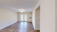 This 770 square foot apartment in Gastonia, NC offers a practical and modern living space. The unit features two bedrooms, including a primary bedroom of 140 square feet, and one bathroom. The layout efficiently utilizes the single-floor design, incorporating a kitchen, living room, two bedrooms, a bathroom, closet, and hallway.

The apartment showcases a blend of contemporary finishes and practical amenities. Rooms feature a mix of plush carpeting and sleek hardwood flooring, providing both comfort and easy maintenance. Ceiling fans in several rooms offer improved air circulation and energy efficiency.

The bathroom is well-appointed with a combination tub-shower, featuring white tile and contrasting dark accent tiles. A wooden vanity with a white countertop provides ample storage space.

The kitchen is equipped with wooden cabinetry and includes modern stainless steel appliances, including a refrigerator. The living area is brightened by French doors leading to an outdoor space, allowing natural light to flood the room.

Large windows in the bedrooms offer views of the surrounding area and ample natural light. Closet space with white doors provides storage solutions throughout the apartment. The neutral color palette of cream walls and white trim creates a bright, open feel throughout the space, allowing for personalization with decor.