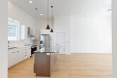 Located at 411 Charles Ave in Charlotte's vibrant Plaza Midwood neighborhood, this contemporary 3-story home offers a thoughtfully designed layout spread across three floors. The ground level houses a spacious attached garage with a utility room, providing convenient access to the home's interior. The main living level features an open-concept kitchen and dining area highlighted by light hardwood floors, soaring ceilings, and an abundance of natural light. The kitchen is appointed with white cabinetry, a subway tile backsplash, stainless steel appliances including a gas range and refrigerator, a wall-mounted range hood, and a striking center island with a dramatic dark stone countertop accented by elegant veining. Pendant lighting adds a modern touch overhead. The upper floors accommodate two well-proportioned bedrooms, each featuring hardwood flooring, natural light from large windows, and ceiling fans. The primary bedroom includes its own dedicated closet. Four bathrooms are distributed throughout the home, with standout bathrooms showcasing geometric patterned tile flooring, dark stone vanity tops, gold and matte black fixtures, glass-enclosed walk-in showers, and white subway tile walls. Clean white walls and natural wood staircases with modern horizontal railings unify the home's contemporary aesthetic throughout all three levels.